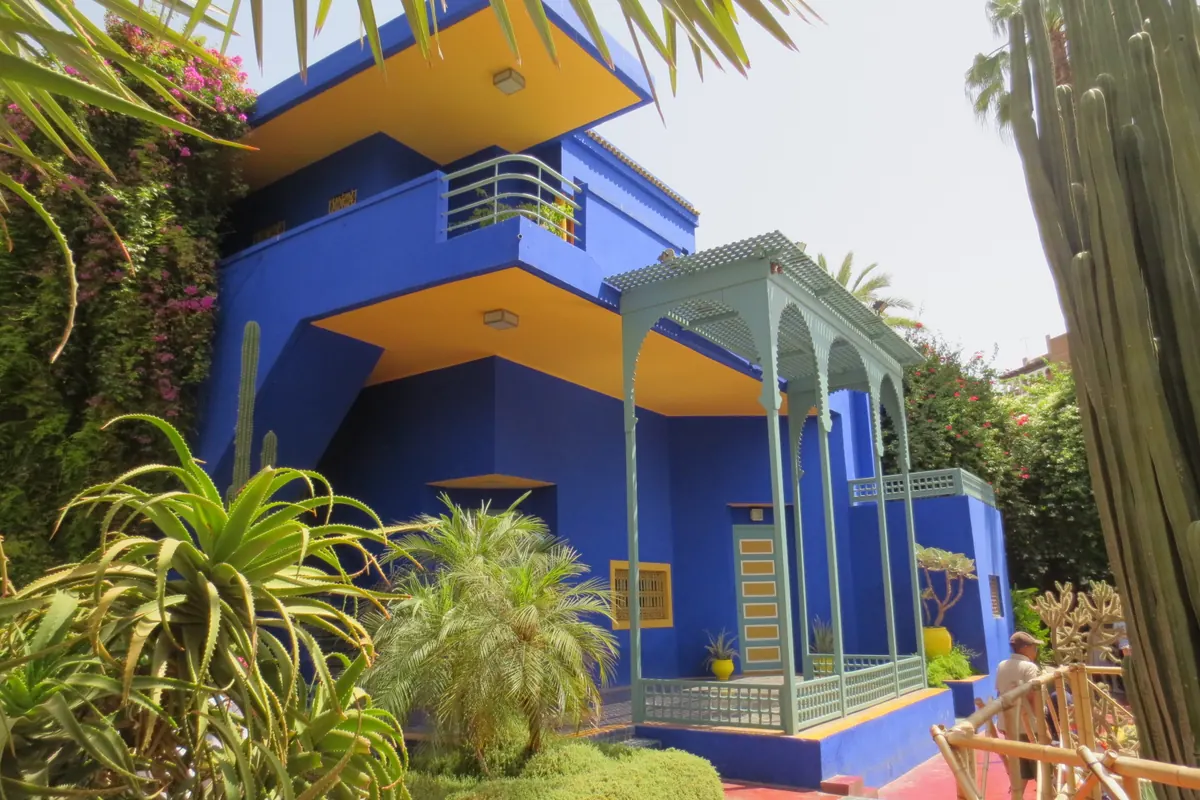 Majorelle 花園的藍色立體主義別墅，黃色陽台天花板、淡綠色遊廊，旁有高聳仙人掌