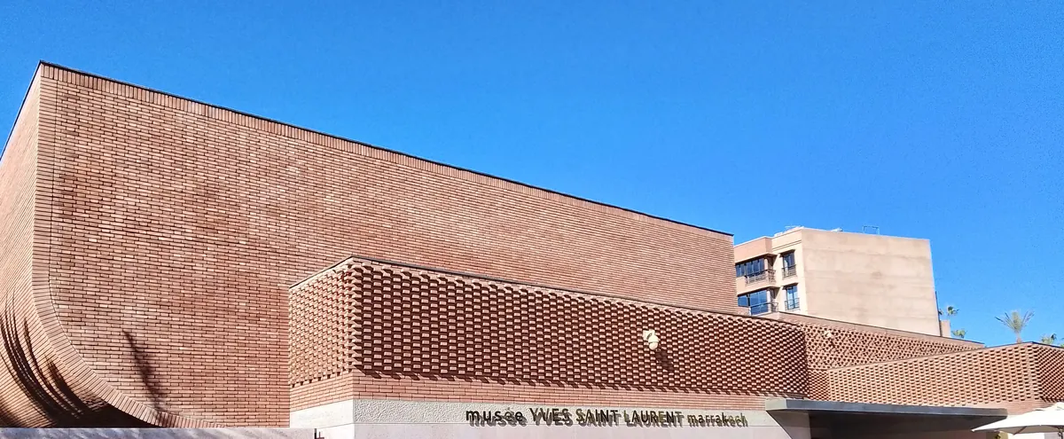 La fachada de ladrillo rojizo del Musée Yves Saint Laurent Marrakech, con su entramado de ladrillo recortado contra un cielo azul